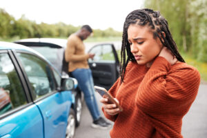 Woman holding neck and making a phone call after a motor vehicle collison.